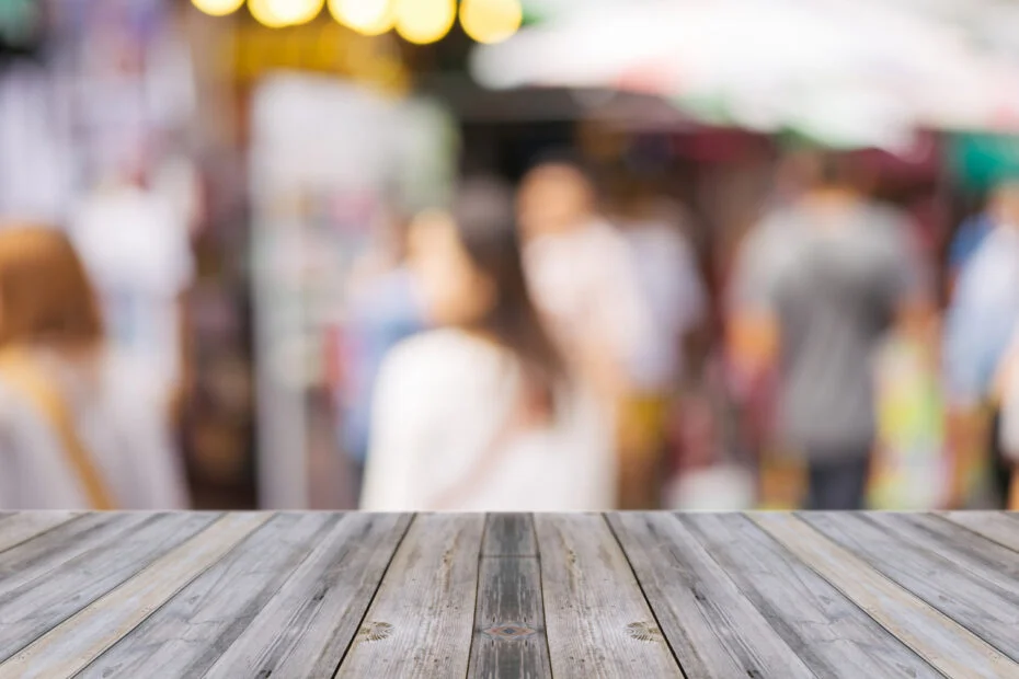 Wooden board empty table in front of people shopping at market f